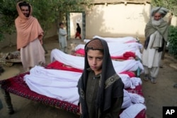 Men and boys stand around the bodies of people killed in an earthquake in Gayan village, Paktika province, Afghanistan, June 23, 2022.