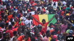 Un partisan brandit un drapeau national guinéen alors que des militants en exil arrivent à Conakry, le 18 septembre 2021.