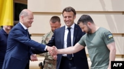 Presiden Ukraina Volodymyr Zelensky (kanan) berjabat tangan dengan Kanselir Jerman Olaf Scholz (kiri) di samping Presiden Prancis Emmanuel Macron sebelum pertemuan mereka di Kyiv, pada 16 Juni 2022. (Foto: AFP)