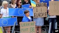 Protestors in support of Ukraine stand with signs and EU flags during a demonstration outside of an EU summit in Brussels, Thursday, June 23, 2022. (AP Photo/Olivier Matthys)