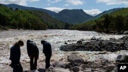 Residents walk along the shore of the elevated Yellowstone River in Gardiner, Montana, which sits at the entrance to Yellowstone National Park, June 15, 2022.