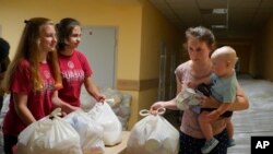 乌克兰东部顿涅茨克地区一名妇女带着孩子在领取当地政府提供的援助物资（2022年6月14日）