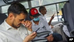 Indian journalist Mohammed Zubair, center, wearing a cap and a face mask, sits in a police vehicle in New Delhi, June 28, 2022.