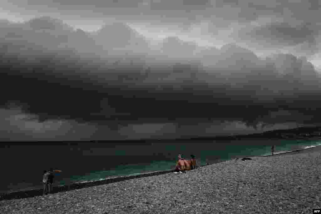 Beach-goers look at the clouds before a storm along the &quot;Promenade des anglais&quot; on the French Riviera city of Nice, June 28, 2022.