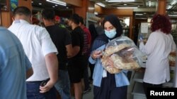 FILE - People queue as a woman carries several loafs of bread at a bakery in Beirut, Lebanon, June 29, 2022.