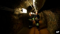 Two researchers walk through an old mining tunnel to what is now the Sanford Underground Research Facility in Lead, S.D., on Dec. 8, 2019. The laboratory houses a dark matter detector. (AP Photo/Stephen Groves)