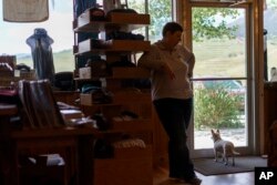 Katie Gale, and her dog, Rory, wait for customers at Paradise Adventure Company which sits across from the entrance to Yellowstone National Park, a major tourist attraction now closed due to the historic floodwaters, Wednesday, June 15, 2022, in Gardiner, Mont.