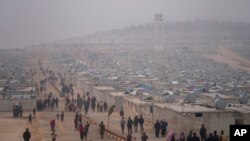 FILE - Syrians walk in a refugee camp for displaced people run by the Turkish Red Crescent in Sarmada district, north of Idlib city, Syria, Nov. 26, 2021.