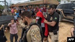 Polisi mengawal tersangka Amarildo da Costa de Oliveira, alias "Pelado" menuju lokasi pencarian jurnalis Inggris Dom Phillips dan pakar pribumi Brazil Bruno Pereira di Atalaia do Norte, negara bagian Amazonas, Brazil, 15 Juni 2022. (Foto: Avener PRADO / Agencia Publica / AFP) 