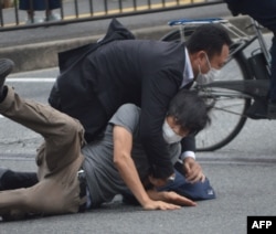 Seorang pria (bawah) yang diduga menembak mantan perdana menteri Jepang Shinzo Abe dijatuhkan oleh polisi di Stasiun Yamato Saidaiji di kota Nara pada 8 Juli 2022. (Foto: AFP)