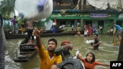 People collect food aid in a flooded residential area following heavy monsoon rainfalls in Companiganj on June 20, 2022. 