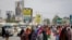 FILE: Somalis walk past billboards showing candidates Abdirahman Abdishakur Warsame and Omar Abdulkadir Ahmedfiqi in Mogadishu, Somalia, Jan. 29, 2021.