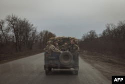 Ukrainian servicemen ride in a military vehicle on a road near the town of Chasiv Yar, Donetsk region, on April 2, 2024. Chasiv Yar is under “constant fire,” local officials say.