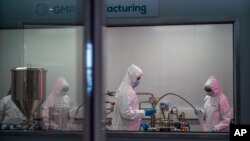 Scientists re-enact the calibration procedure of equipment at an Afrigen Biologics and Vaccines facility in Cape Town, South Africa, Tuesday Oct. 19, 2021. (AP Photo/Jerome Delay)