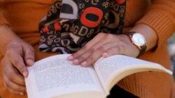 An Afghan woman living in Massachusetts who identified herself only as Bahara and asked her last name be withheld over concerns for her family, holds a book Nov. 9, 2021, during an interview with The Associated Press.