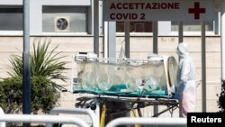 A medical worker in a protective suit stands with an isolation stretcher in front of the Columbus Clinic, where patients suffering from coronavirus disease (COVID-19) were moved from Spallanzani Hospital, in Rome, Italy, March 16, 2020. 