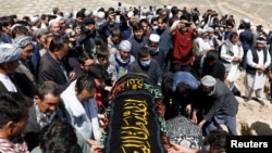 Afghan men prepare victims' coffins for a mass funeral ceremony after yesterday's explosion in Kabul, Afghanistan, May 9, 2021. 