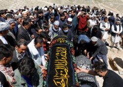 Afghan men prepare victims' coffins for a mass funeral ceremony after yesterday's explosion in Kabul, Afghanistan, May 9, 2021.