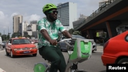 The Ivorian environmental activist Andy Costa also known as the cycling ambassador in Africa, pedals his bike among cars in a street of the central business district of Plateau in Abidjan, Ivory Coast July 24, 2020. (REUTERS/Luc Gnago)