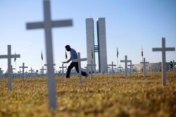 An activist walks past crosses symbolising the ones who died from the coronavirus disease (COVID-19) in front of the National Congress during a protest against Brazil's President Jair Bolsonaro in Brasilia, Brazil June 28, 2020.