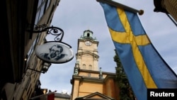 FILE - Sweden's flag is seen near the Stockholm Cathedral in Gamla Stan or the Old Town district of Stockholm, Sweden. For the first time since record-keeping began in 1749, Sweden now has more men than women.