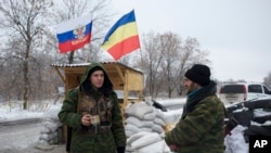 Pemberontak pro-Rusia menjaga pos pemeriksaan berhiaskan bendera Rusia dan resimen Don Cossacks di luar kota Pervomaisk, Ukraina timur (6/12). (AP/Balint Szlanko)