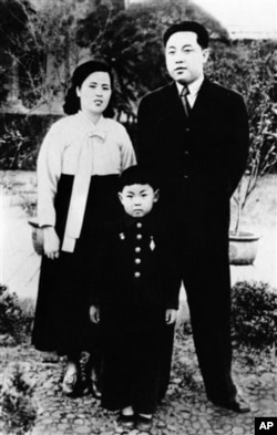 朝鲜中央通讯社未注明日期的照片: 金正日(中)童年时期与父母合影。左边是母亲金正淑，右边是父亲金日成。