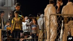 FILE - Migrants wait to disembark from the Italian Navy Ship "Grecale" at Pozzallo harbor, Sicily, May 13, 2014. 