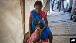 In this Dec. 31, 2013 file photo, Nyanhial, 5, is comforted by her mother as she is treated for fever and vomiting at a Doctors Without Borders medical tent in the Jebel area on the outskirts of Juba, South Sudan. Human Rights Watch says the more than year long conflict has taken a heavy toll on civilians. HRW calls on the AU to release its commission of inquiry report on the conflict. (AP Photo/Ben Curtis, File)