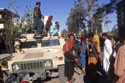 Taliban fighters stand guard along the roadside in Herat, Afghanistan's third biggest city, after government forces pulled out the day before following weeks of being under siege, Aug. 13, 2021.