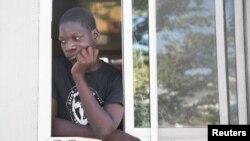 A man looks out from a window as people fleeing from violence after the murder of a local gang leader camp out in the courtyard of Cite Soleil's town hall, in Port-au-Prince, Haiti, Dec. 7, 2019. 