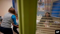 Brooklynn Chiles, 8, is examined during a followup visit at Children's National Hospital in Washington, Friday, Feb. 11, 2022, as her mother, Danielle watches.