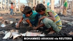 Children look at debris after a fire outbreak in Rohingya refugee camp, in Cox's Bazar, Bangladesh, Jan. 14, 2021.