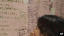 A woman looks at a message board to check for evacuees in Rikuzentakata, northern Japan, Tuesday, March 15, 2011, four days after a powerful earthquake-triggered tsunami hit the country's east coast.