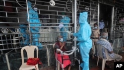 18일 인도 뭄바이의 한 신전 앞에서 의료진이 코로나 감염 여부를 확인하기 위해 노인의 체온을 측정하고 있다.