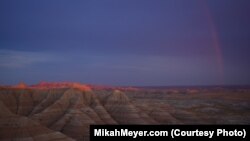 After a storm, a rainbow lights the rugged peaks of the Badlands National Park.