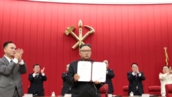 김정은 북한 국무위원장이 지난 6월 노동당 중앙위원회 제8기 제3차 전원회의 3일차 회의에서 서명한 문서를 들어보이고 있다.