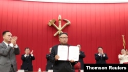 지난 6월 북한 평양에서 열린 노동당 중앙위원회 제8기 제3차 전원회의 3일차 회의에서 김정은(가운데) 국무위원장이 서명한 문서를 들어보이고 있다.