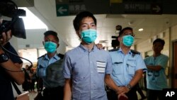 An Occupy Central protester, center, is escorted by police to a hospital for examine his injury during a clash between protesters and police in an occupied area near the government headquarters in Hong Kong, Oct. 15, 2014.