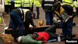 Police officers work to remove protesters who had chained themselves to a homemade coffin close to the entrance of the IGas exploratory gas drilling site at Barton Moss, near Manchester, northern England, March 6, 2014