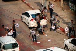 Police officers clear the road after demonstrators spread placards in Yangon, Myanmar, Saturday, April 24, 2021.