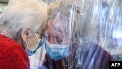 FILE - A resident, left, of the Domenico Sartor nursing home in Castelfranco Veneto, near Venice, Italy, hugs her visiting daughter Nov. 11, 2020, through a plastic screen in a so-called 'Hug Room' amid the new coronavirus pandemic.