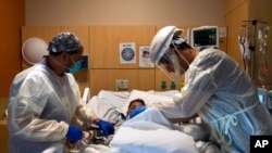 FILE - Medical personnel check on a COVID-19 patient at Providence Holy Cross Medical Center in Los Angeles, Nov. 19, 2020. With coronavirus cases surging, California Gov. Gavin Newsom announced a new stay-at-home order Dec. 3, 2020.