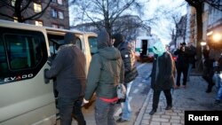 Media surround German special police as they enter their vehicle after a raid of an apartment building in the Wedding district in Berlin, January 16, 2015.