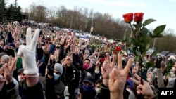 People flash the V-sign to pay tribute to late opposition protester Raman Bandarenka during his funeral ceremony in Minsk, Belarus on November 20, 2020.