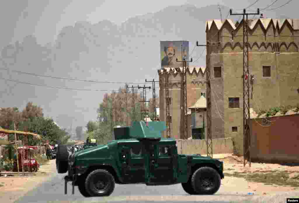 Afghan policemen stand guard near the house belonging to Afghan President Hamid Karzai&#39;s cousin, Hashmat Karzai, at the site of a suicide attack in Kandahar, Afghanistan, July 29, 2014.