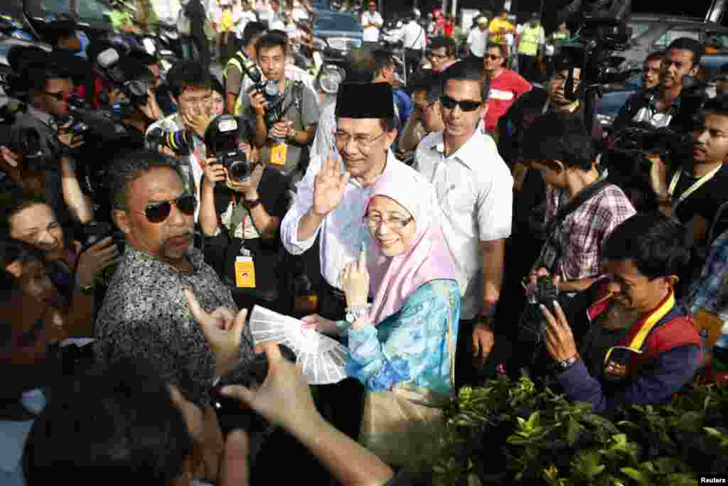 Pemimpin oposisi Anwar Ibrahim meninggalkan tempat pemungutan suara bersama istrinya Wan Azizah Wan Ismail setelah mencoblos dalam pemilihan umum di Permatang Pauh (5/5). 