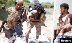 A fighter of Libyan forces allied with the U.N.-backed government runs for cover with another fighter while carrying a wounded fighter during a battle with Islamic State fighters in Sirte, Libya, July 31, 2016.