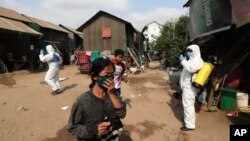 រូបឯកសារ៖ ពលរដ្ឋនៅក្នុងសង្កាត់ស្ទឹងមានជ័យដើរចេញពីកន្លែង ដែលបុគ្គលិកប្រចាំអង្គការមូលនិធិកុមារកម្ពុជា (CCF) កំពុងបាញ់ថ្នាំសម្លាប់មេរោគដើម្បីជួយទប់ស្កាត់ការឆ្លងរាលដាលនៃវីរុសកូរ៉ូណាប្រភេទថ្មី នៅតំបន់ស្ទឹងមានជ័យ ជាយរាជធានីភ្នំពេញ ថ្ងៃទី២៤ ខែមីនា ឆ្នាំ២០២០។ 