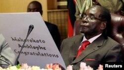 Former Zimbabwe's President Robert Mugabe reads a card during his 93rd birthday celebrations in Harare, Feb. 21, 2017. 